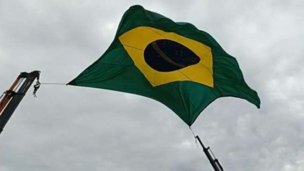 Caminhoneiros cantam o hino nacional debaixo de grande bandeira do Brasil